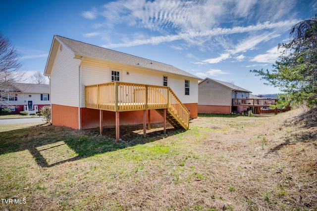 back of house with stairway, a wooden deck, and a lawn