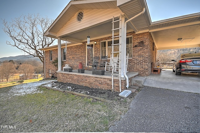 exterior space with driveway, brick siding, a porch, and an attached carport