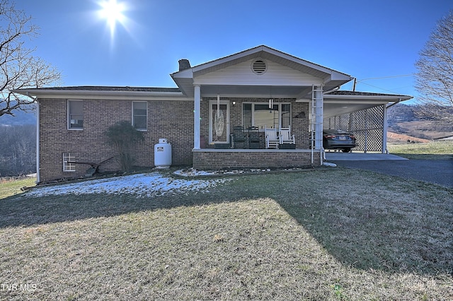 view of front of home featuring a carport, brick siding, a chimney, and a front yard