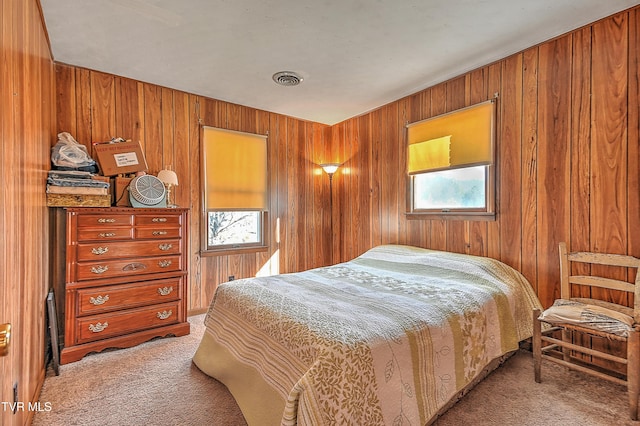 bedroom featuring wood walls, visible vents, and light colored carpet