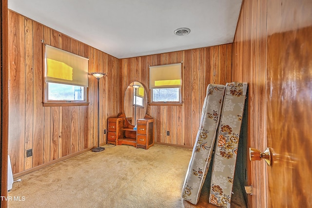 interior space featuring baseboards, visible vents, wood walls, and carpet flooring