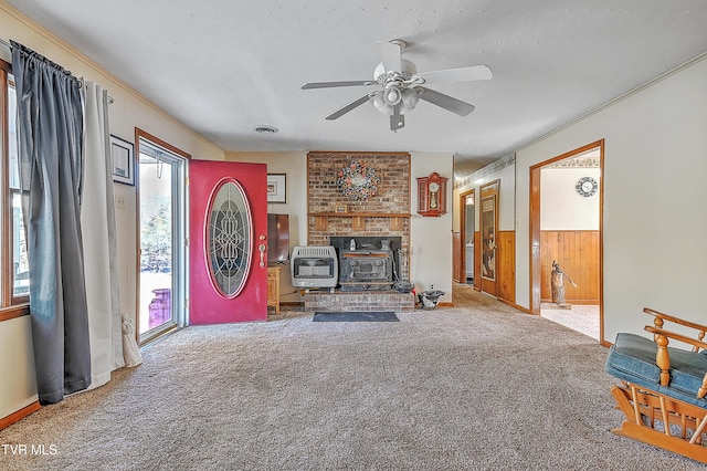 living room featuring a wood stove, carpet flooring, wood walls, and heating unit