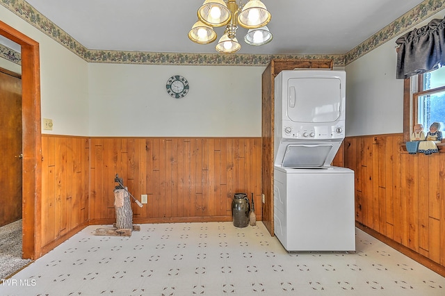 washroom with laundry area, wooden walls, a wainscoted wall, stacked washer / drying machine, and tile patterned floors