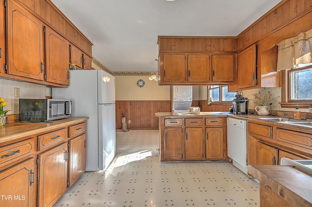 kitchen featuring light floors, white appliances, wainscoting, and brown cabinets