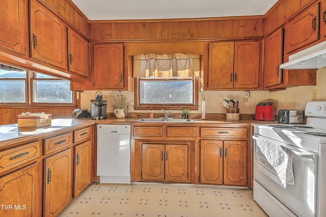 kitchen featuring white appliances, a sink, and brown cabinets