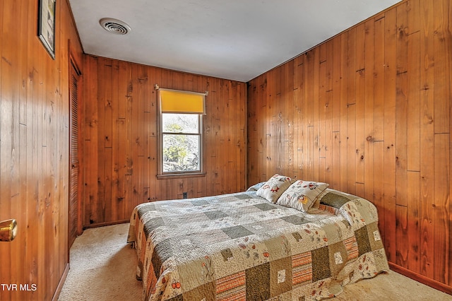 carpeted bedroom featuring wood walls, visible vents, and baseboards