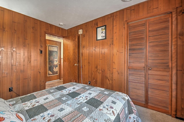 carpeted bedroom with a closet and wood walls