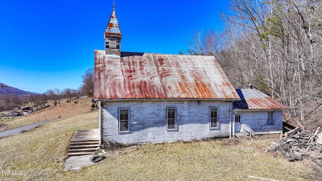 rear view of house featuring metal roof and a lawn