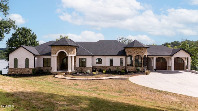 french country style house with a garage, a front yard, concrete driveway, and a shingled roof