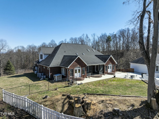 back of house with brick siding, a fenced backyard, a lawn, and a patio area