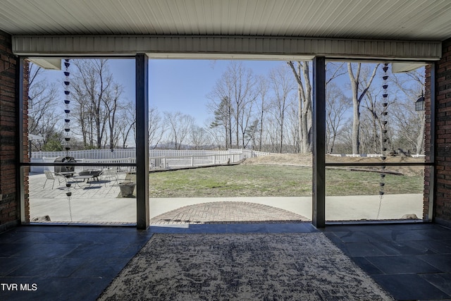 doorway to outside featuring plenty of natural light and brick wall