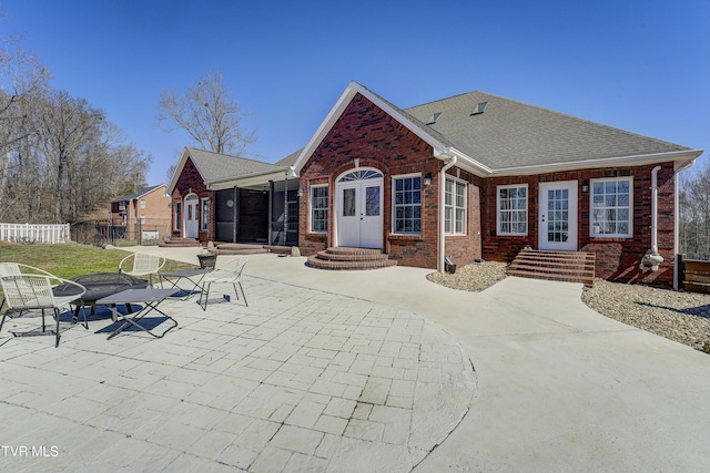 back of house with brick siding, fence, entry steps, roof with shingles, and french doors