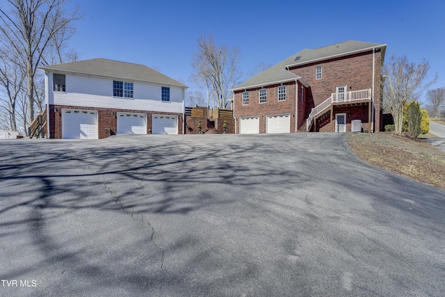 view of side of property with aphalt driveway, stairway, a garage, and brick siding