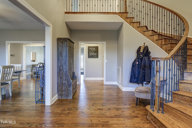 foyer entrance featuring baseboards, wood finished floors, and stairs