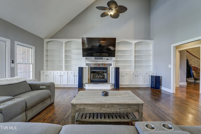 living area with a towering ceiling, baseboards, dark wood-style flooring, and a tiled fireplace