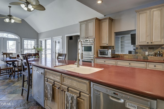 kitchen with lofted ceiling, a toaster, stone finish floor, appliances with stainless steel finishes, and backsplash