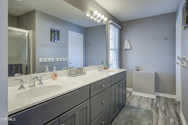 full bath with a shower stall, wood finished floors, baseboards, and a sink