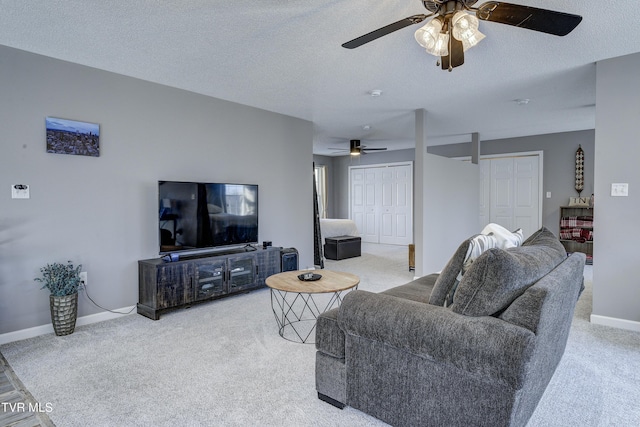 living area featuring ceiling fan, carpet, baseboards, and a textured ceiling