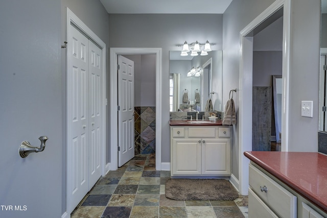 bathroom with vanity, a closet, a tile shower, and stone finish flooring