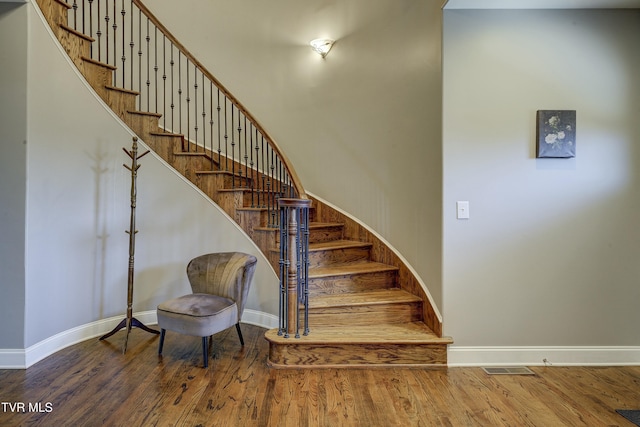 stairs with visible vents, baseboards, and wood finished floors