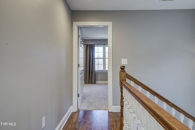 corridor featuring an upstairs landing, visible vents, dark wood-type flooring, and baseboards