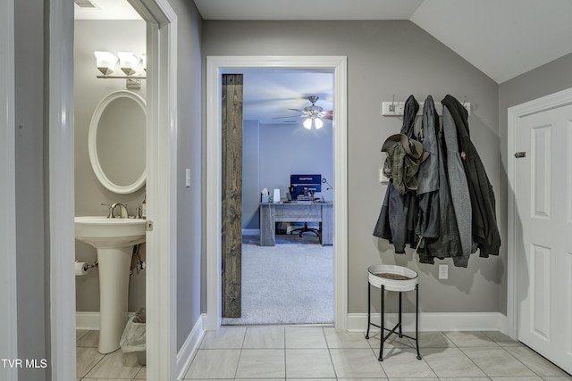 hall with vaulted ceiling, light tile patterned flooring, and baseboards