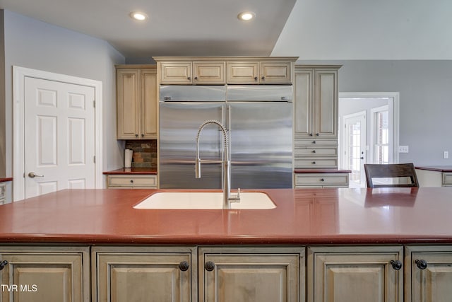 kitchen with tasteful backsplash, a kitchen island with sink, stainless steel built in refrigerator, recessed lighting, and a sink