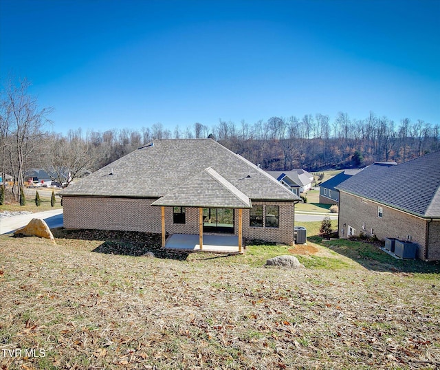 back of property featuring a patio area, brick siding, and roof with shingles