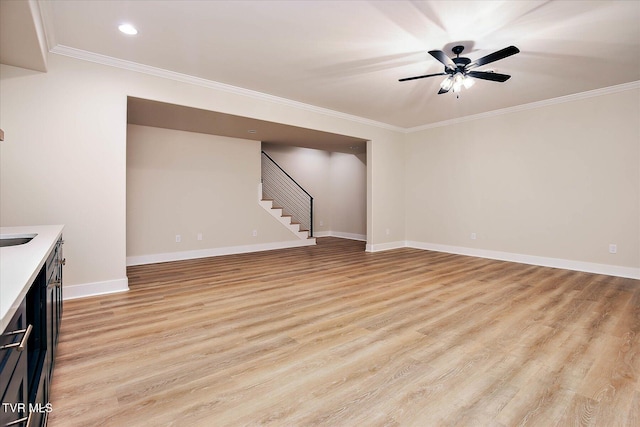 unfurnished living room with a ceiling fan, baseboards, stairs, light wood-style floors, and crown molding