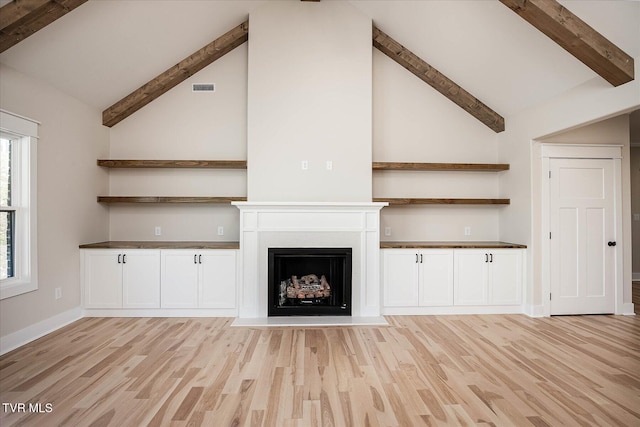 unfurnished living room with lofted ceiling with beams, visible vents, a fireplace with flush hearth, and light wood-style flooring