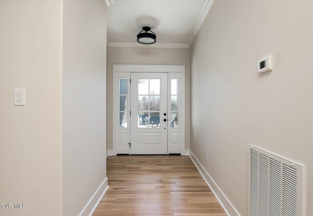 doorway to outside featuring light wood finished floors, baseboards, visible vents, and crown molding