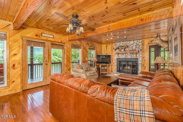 living room featuring wood walls, wooden ceiling, a fireplace, and hardwood / wood-style flooring