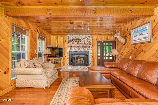 living room featuring wooden ceiling, wooden walls, a fireplace, and beam ceiling