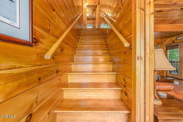 stairway featuring wooden ceiling and wooden walls