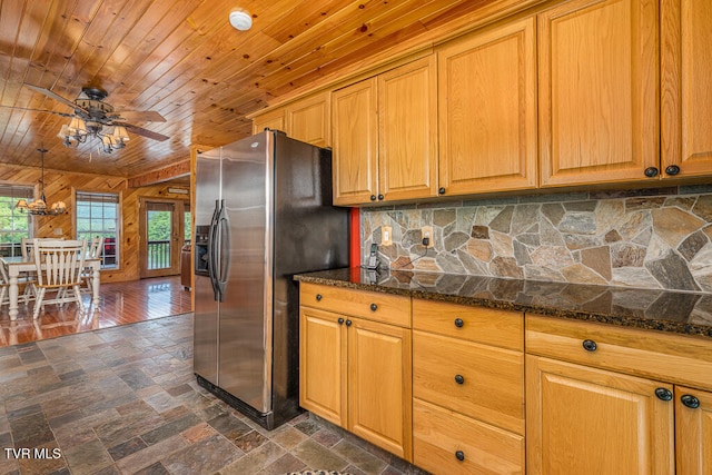 kitchen with brown cabinets, tasteful backsplash, wood ceiling, dark stone counters, and stainless steel fridge