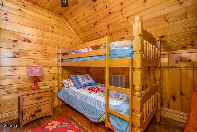 bedroom featuring lofted ceiling, wooden ceiling, wooden walls, visible vents, and dark wood finished floors