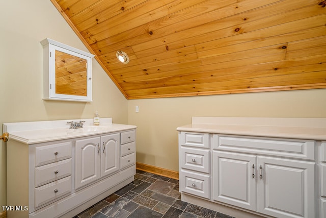 bathroom with baseboards, wooden ceiling, vaulted ceiling, stone tile flooring, and vanity