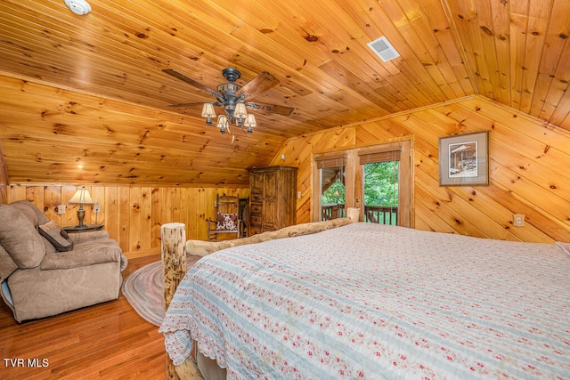 bedroom with access to outside, wood finished floors, and wooden walls