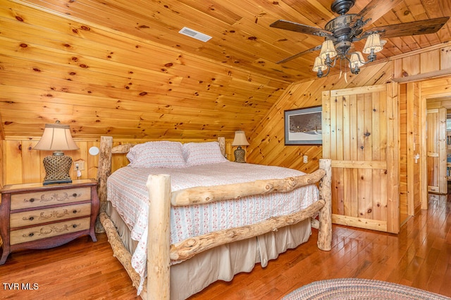 bedroom featuring lofted ceiling, visible vents, wood ceiling, wooden walls, and hardwood / wood-style flooring