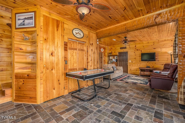 playroom with ceiling fan, beamed ceiling, wood ceiling, and wooden walls