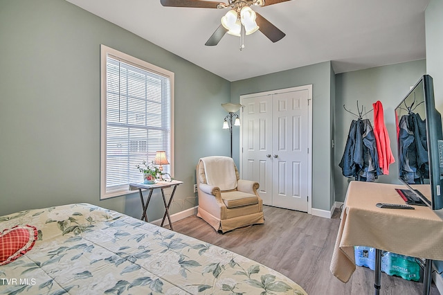 bedroom with a closet, wood finished floors, a ceiling fan, and baseboards