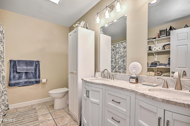 bathroom featuring baseboards, double vanity, a sink, and tile patterned floors