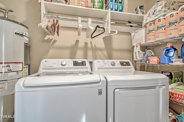 washroom with laundry area, washing machine and clothes dryer, and electric water heater