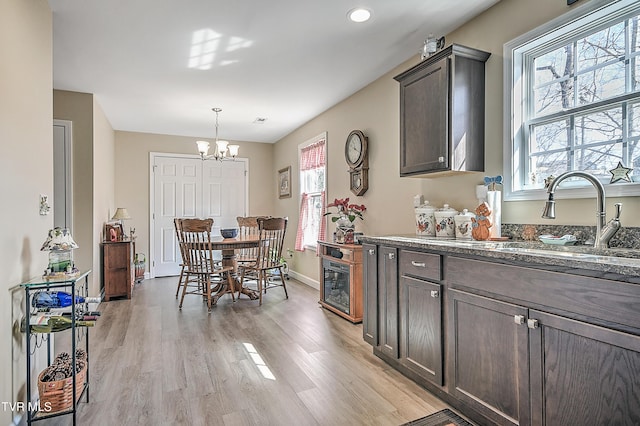 dining room featuring baseboards, light wood finished floors, a wealth of natural light, and a notable chandelier