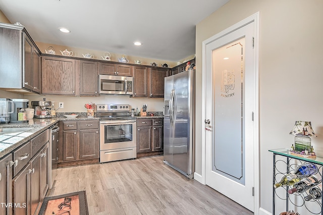 kitchen featuring dark brown cabinetry, light stone countertops, stainless steel appliances, light wood-type flooring, and recessed lighting