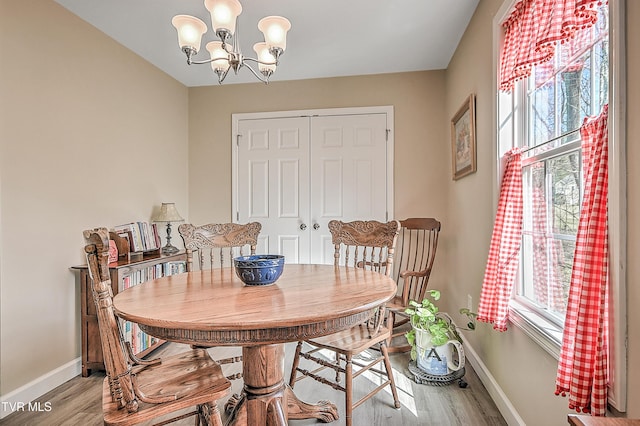 dining space featuring light wood-style floors, baseboards, and an inviting chandelier