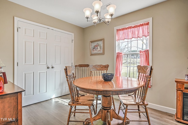 dining room with baseboards, a notable chandelier, and light wood finished floors