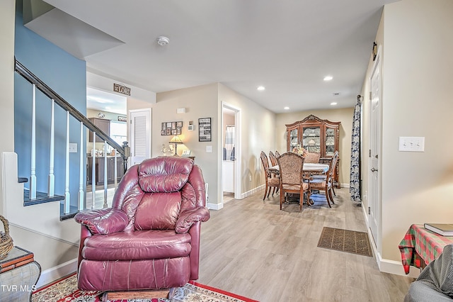 living room featuring light wood finished floors, stairs, baseboards, and recessed lighting