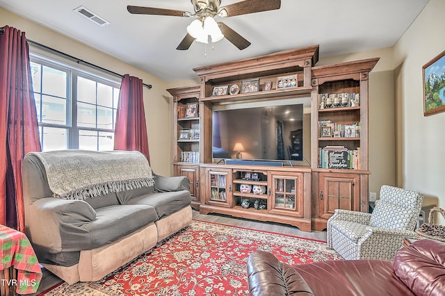 living area with a ceiling fan, visible vents, and wood finished floors