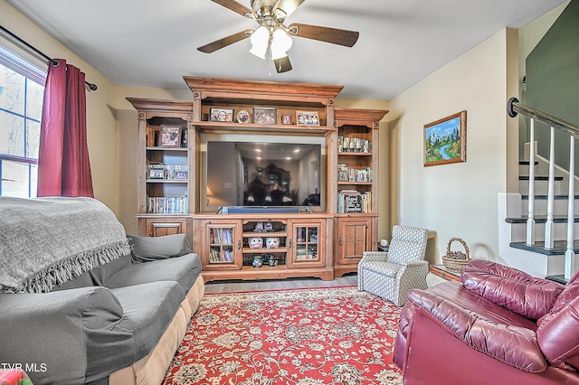 living room with a ceiling fan and stairs